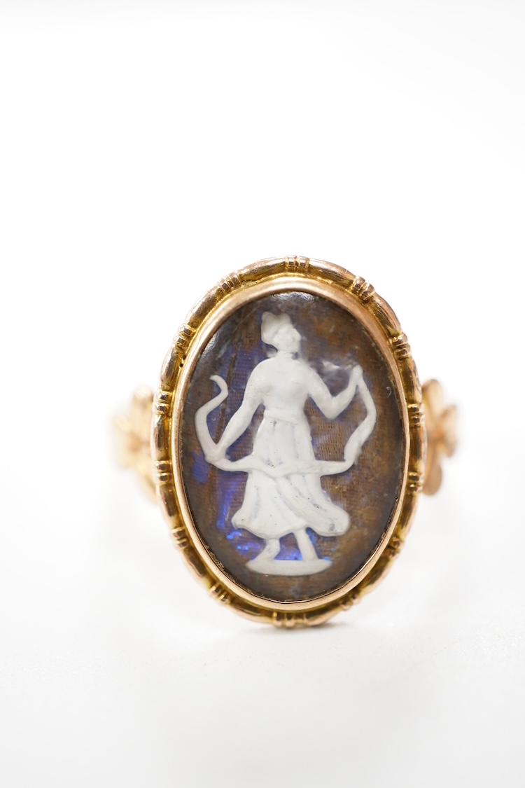 An early 20th century 9ct oval ring, decorated with the figure of a lady in relief, on a butterfly wing ground, beneath a glazed panel, size K, gross weight 2.3 grams.